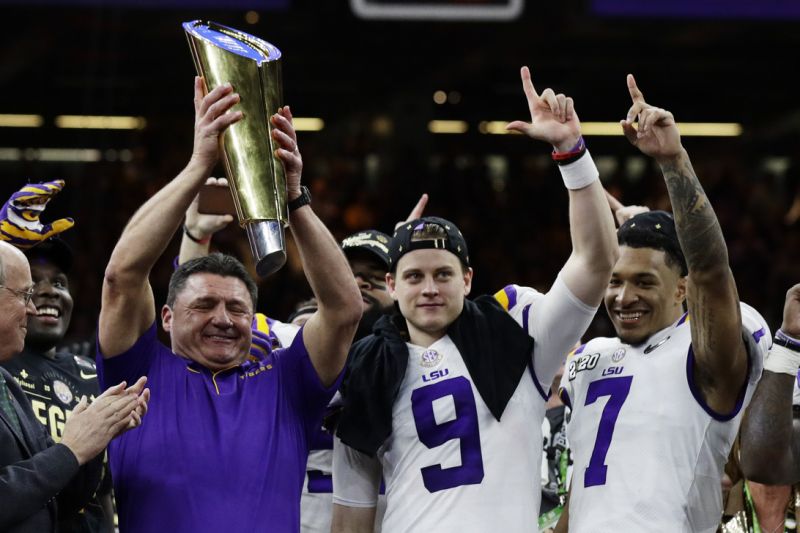 يحمل مدرب LSU Ed Orgeron الكأس بجانب لاعب الوسط جو بورو ، في المركز ، وجرانت ديلبت بعد مباراة البطولة الوطنية NCAA College لكرة القدم ضد كليمسون ، الاثنين 13 يناير 2020 ، في نيو أورليانز. فاز LSU 42-25. (AP Photo / Sue Ogrocki)