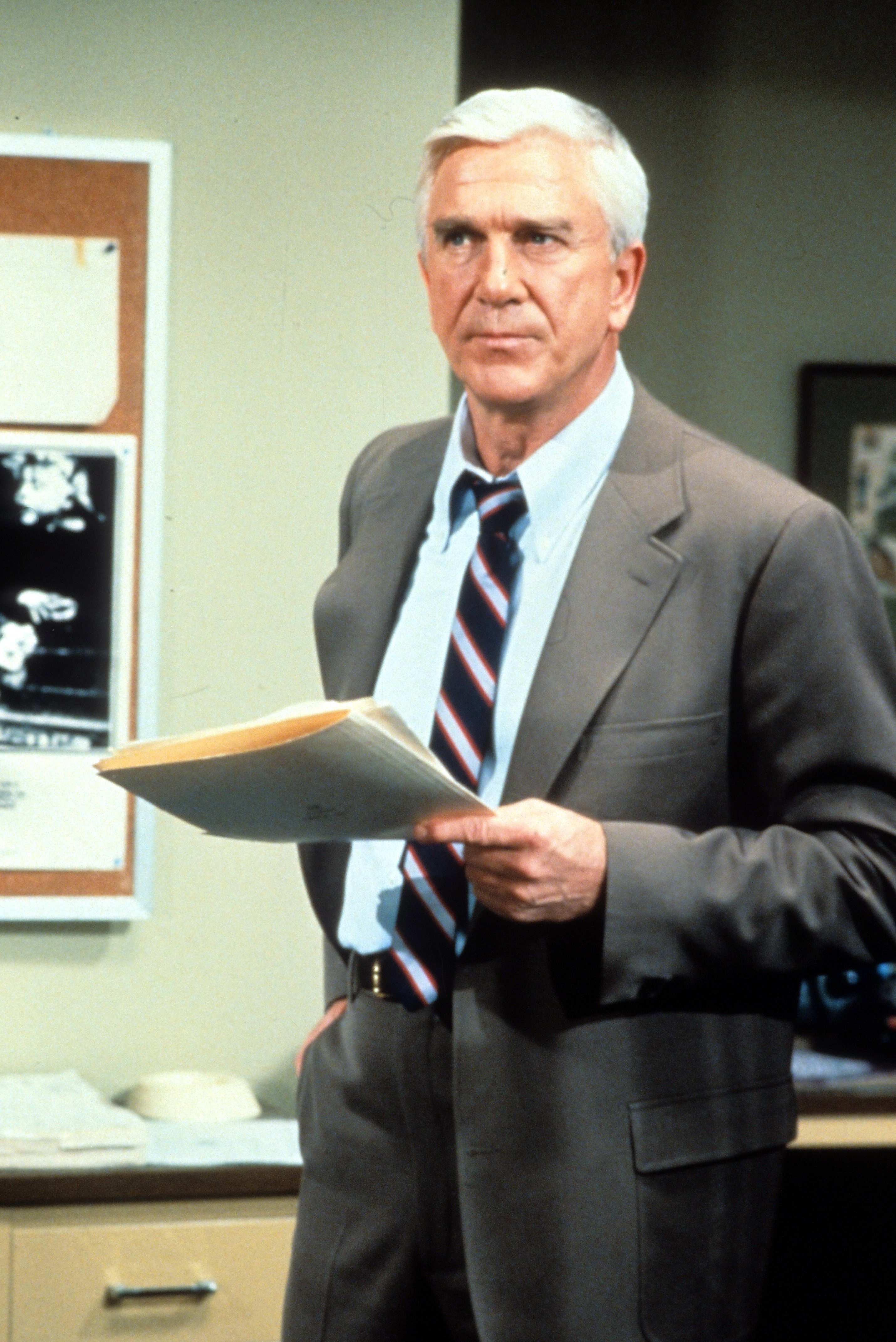 Leslie Nielsen holding folders in a scene from the television series 'Police Squad!', 1982. (Photo by Paramount/Getty Images)