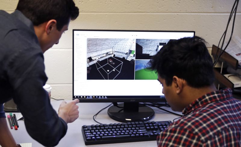 طالبات بوسطن كوليدج إيفان أوتيرو ، على اليسار ، وإماد علي يشاهدان محطة عمل في مختبر الواقع الافتراضي في بوسطن. يقوم طلاب الجامعات في بوسطن بتطوير لعبة الواقع الافتراضي استنادًا إلى كتاب جيمس جويس الرائع 